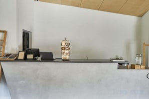 A reception desk with a laptop, a decorative vase, and a small table with a glass container. - Pana Ayusai (Almaty)