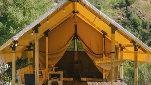 Una carpa amarilla con una terraza de madera y un letrero que dice 'Ayutas'.