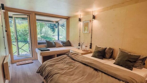 Un dormitorio con una cama grande, un escritorio y vistas al exterior a través de una puerta corrediza.