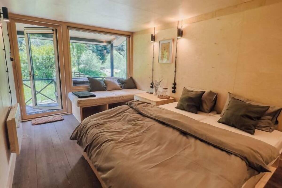 Une chambre avec un grand lit, un bureau et une vue sur l’extérieur grâce à une porte coulissante.