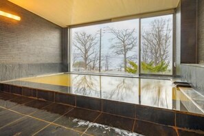 A modern indoor hot tub with a view of bare trees through large windows. - Toyako Villa Susukian (Usu District)