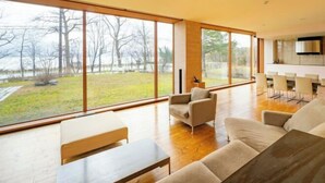 A spacious living area with large windows, a wooden floor, and a modern kitchen in the background. - Toyako Villa Susukian (Usu District)