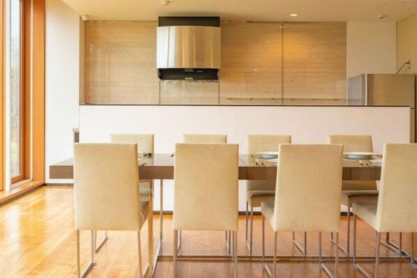 Une cuisine moderne dotée d’un îlot central, d’un coin repas avec six chaises et d’une grande fenêtre qui laisse entrer la lumière naturelle.