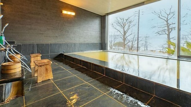A modern spa room with a large glass window, a wooden bench, and a stone floor. - Toyako Villa Susukian (Usu District)
