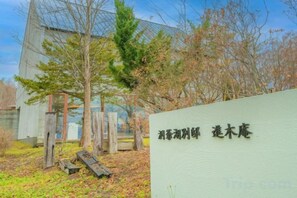A building with a sign in front, surrounded by trees and a wooden structure. - Toyako Villa Susukian (Usu District)