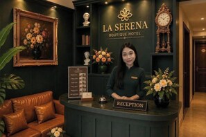 Un comptoir d'accueil à l'hôtel La Serena Boutique, agrémenté d'une enseigne, d'œuvres d'art encadrées et d'une horloge.