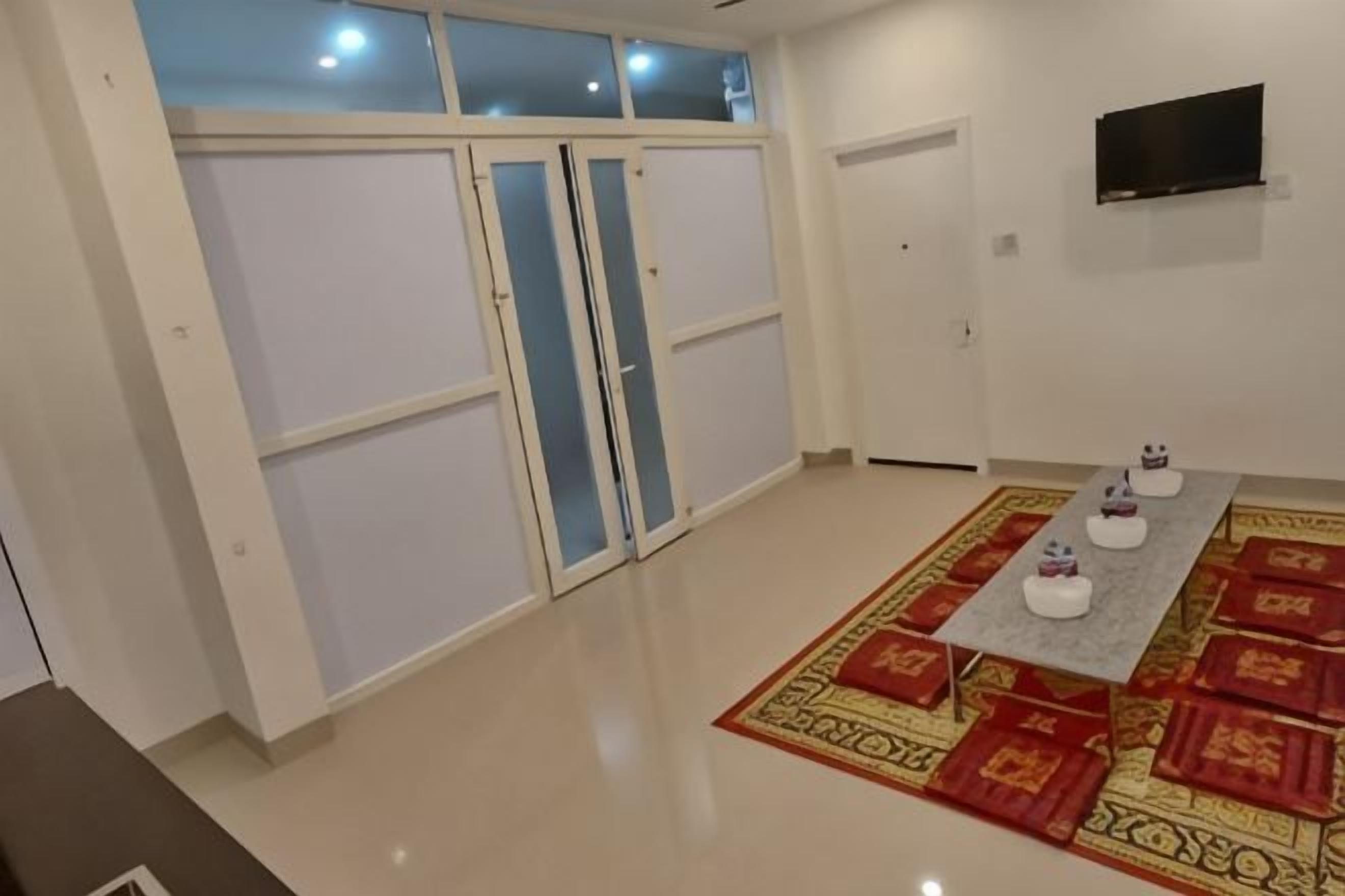 A room with a sliding door, a flat-screen TV mounted on the wall, and a patterned rug on the floor.