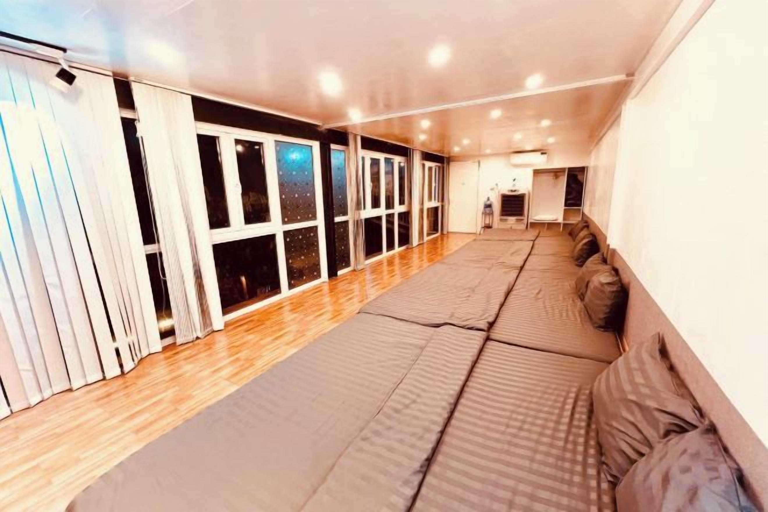 A room with a long bed, a sliding door, and a view through the window.