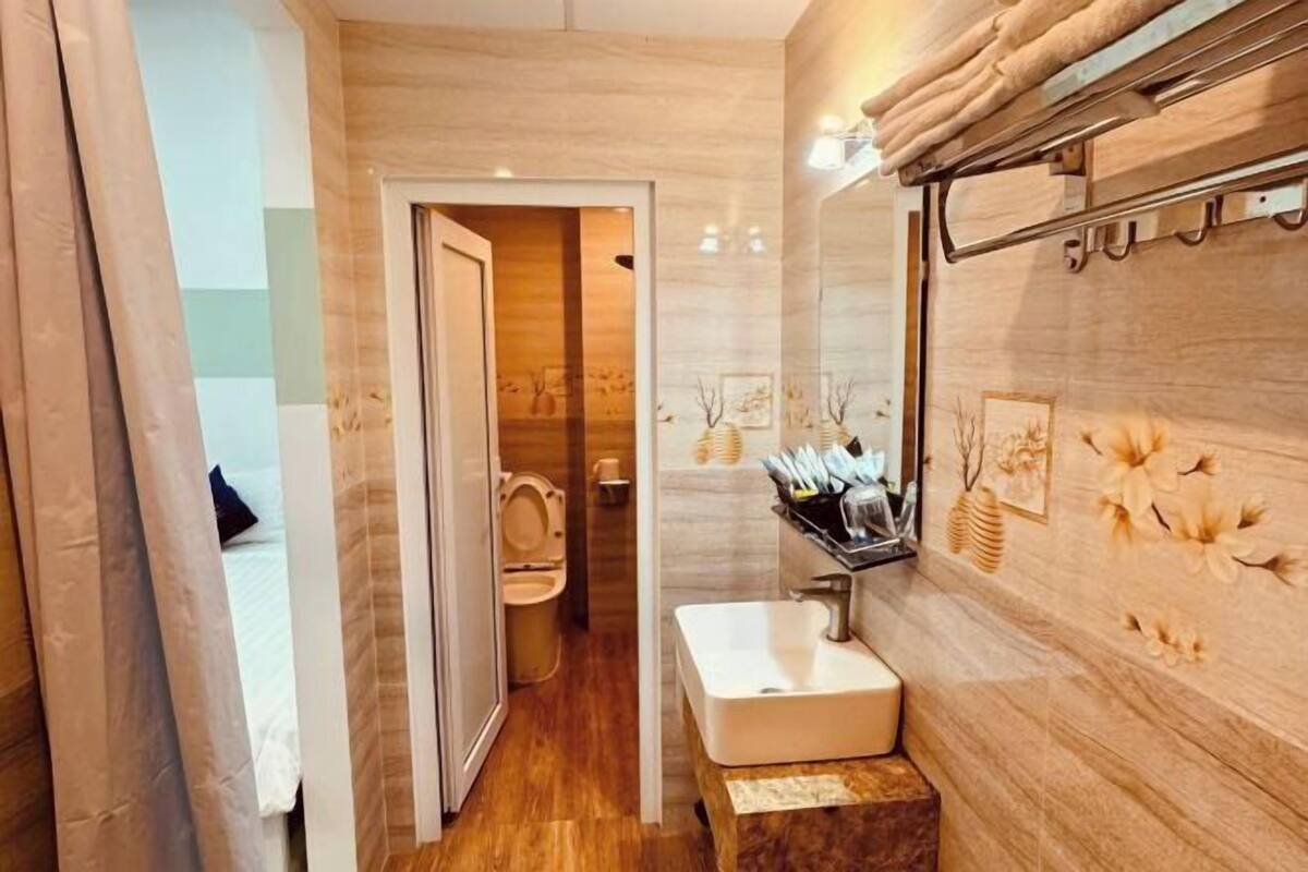 A bathroom with a wooden vanity, a sink, and a toilet visible through an open door.