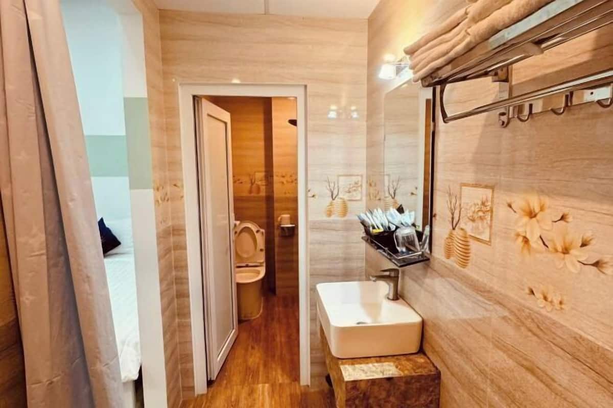 Une salle de bain avec un meuble-lavabo en bois, un évier et des toilettes visibles à travers une porte ouverte.