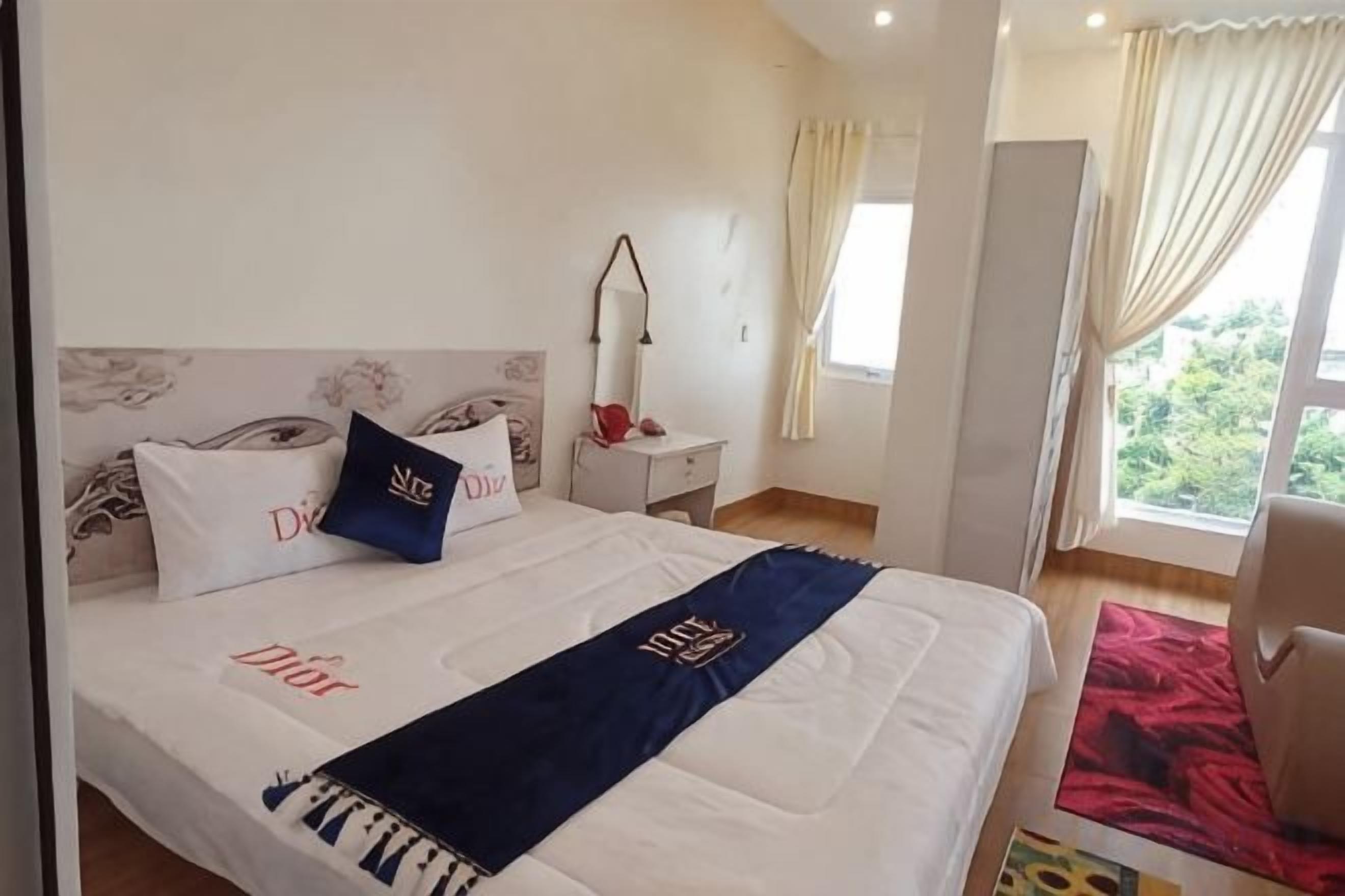 A hotel room with a bed, nightstand, and a window with curtains.