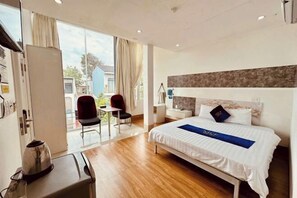 A hotel room with a bed, a desk, a chair, and a view of the outside. - Nice Hotel Buon Ma Thuot (Tu An)