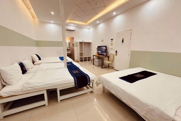 Une chambre d’hôtel avec deux lits, un bureau, une télévision et une porte.