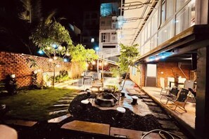 An outdoor courtyard with a brick wall, a small garden, and a staircase leading to an upper level. - Nice Hotel Buon Ma Thuot (Tu An)