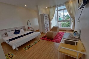 A bedroom with a bed, bedside table, lamp, and a view of the outdoors.