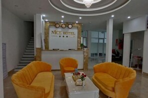 A hotel reception area with a reception desk, two sofas, and a coffee table.