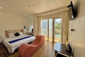 A hotel room with a bed, a desk, a chair, a TV, and a balcony with a view.