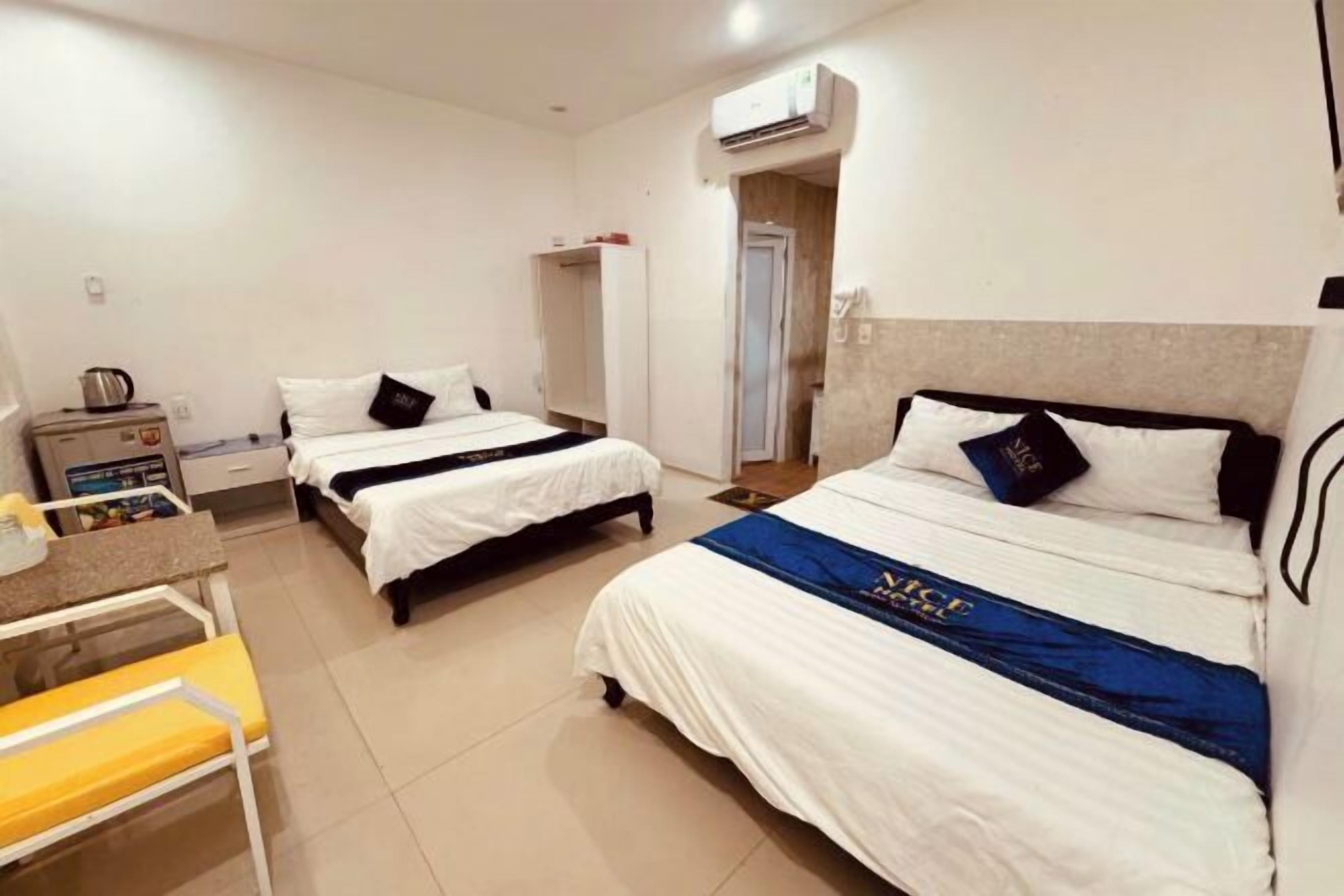 Une chambre d’hôtel avec deux lits, un bureau, une chaise et une petite table.