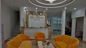 Ein Hotel-Empfangsbereich mit einer Rezeption, zwei Sofas und einer Kristallleuchter.