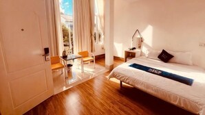 Ein Hotelzimmer mit Bett, Schreibtisch, Stuhl und einem Fenster mit Vorhängen.