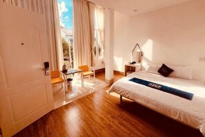 A hotel room with a bed, a desk, a chair, and a window with curtains. - Nice Hotel Buon Ma Thuot (Tu An)