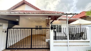 A residential property with a gated entrance, a covered patio area, and a staircase leading to the upper floor. - Valley 41 - 2 bdr Private Villa Near Phuket Town (Kathu)