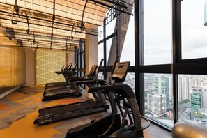 A gym with treadmills and exercise equipment, large windows with a city view, and a modern industrial ceiling design. - SCARLETZ BY FEEL HOME (Kuala Lumpur)