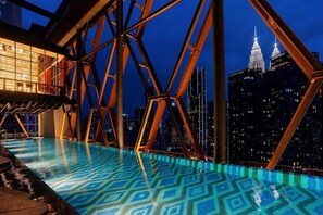 A rooftop pool with a geometric pattern on the floor, surrounded by a steel framework, overlooking a cityscape with skyscrapers. - SCARLETZ BY FEEL HOME (Kuala Lumpur)