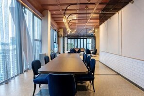 Ein Konferenzraum mit einem langen Tisch, Stühlen und großen Fenstern.