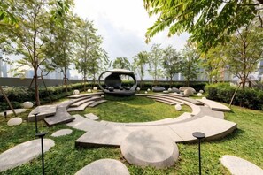 A landscaped garden with a circular seating area, stone pathways, and trees. - SCARLETZ BY FEEL HOME (Kuala Lumpur)
