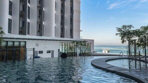 A modern building with a pool area, large windows, and a view of the ocean. - Grace Suite @ The Shore Kota Kinabalu (Kota Kinabalu)