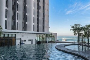 A modern building with a pool area, large windows, and a view of the ocean. - Grace Suite @ The Shore Kota Kinabalu (Kota Kinabalu)