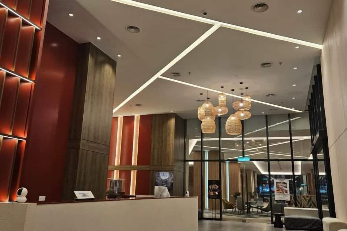 Un moderno vestíbulo de hotel con mostrador de recepción, zona de estar e iluminación contemporánea.