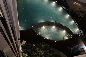 Una piscina circular con una persona caminando alrededor, rodeada por una estructura curva con luces.