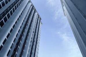 Un immeuble de grande hauteur doté d’une architecture moderne, caractérisé par une série de lignes verticales et de fenêtres rectangulaires.