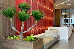 A reception area with a wooden reception desk, a sofa, and a wall with vertical red panels.
