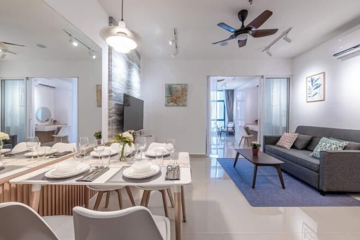 Una sala de estar moderna con comedor, un sofá gris, un ventilador de techo y un televisor.