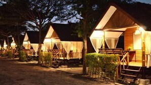 A row of wooden cabins with balconies, each with a small garden area and a staircase leading to the entrance. - Ingnaam Thajeen (Si Prachan)