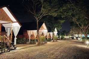 A row of wooden cabins with a gravel path leading to them, surrounded by trees. - Ingnaam Thajeen (Si Prachan)