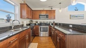 A modern kitchen with wooden cabinets, stainless steel appliances, and a large window providing a view of the outside.