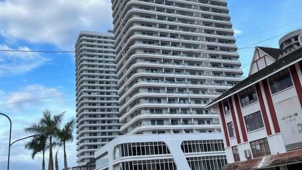 Un edificio moderno e slanciato, caratterizzato da una facciata curva, numerosi balconi e un rivestimento misto di vetro e pannelli solidi.