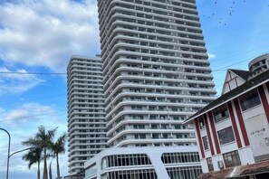 A tall, modern building with a curved facade, multiple balconies, and a mix of glass and solid panels. - THE MOON HOTEL (Boten)
