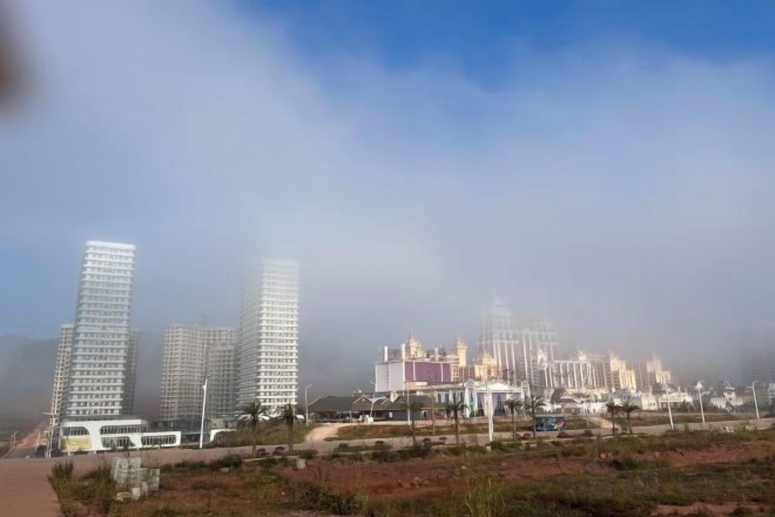 A cityscape with high-rise buildings and a large, multi-story structure in the distance.