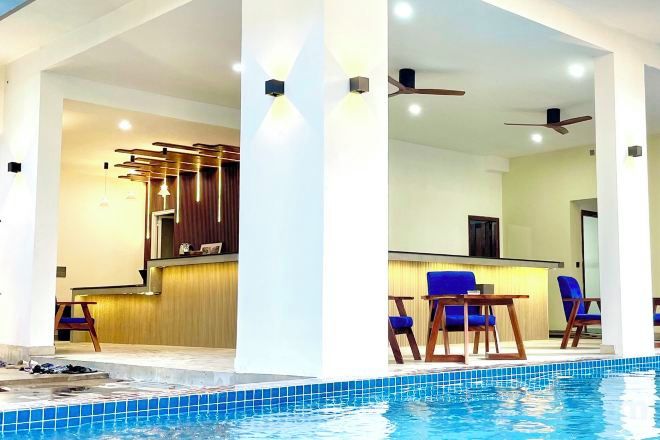 Una piscina interior con zona de bar, asientos y ventiladores de techo.