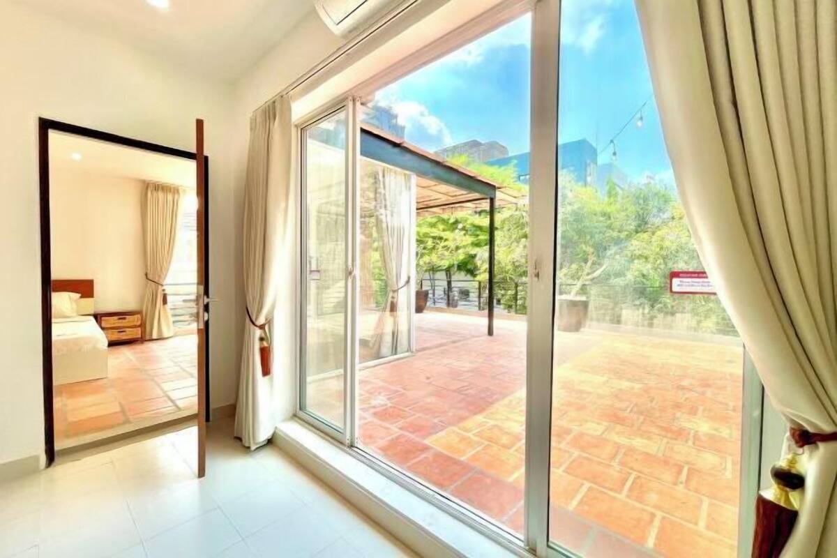 Ein Hotelzimmer mit einer Schiebetür zu einer Terrasse mit Pflasterboden und Bepflanzung.