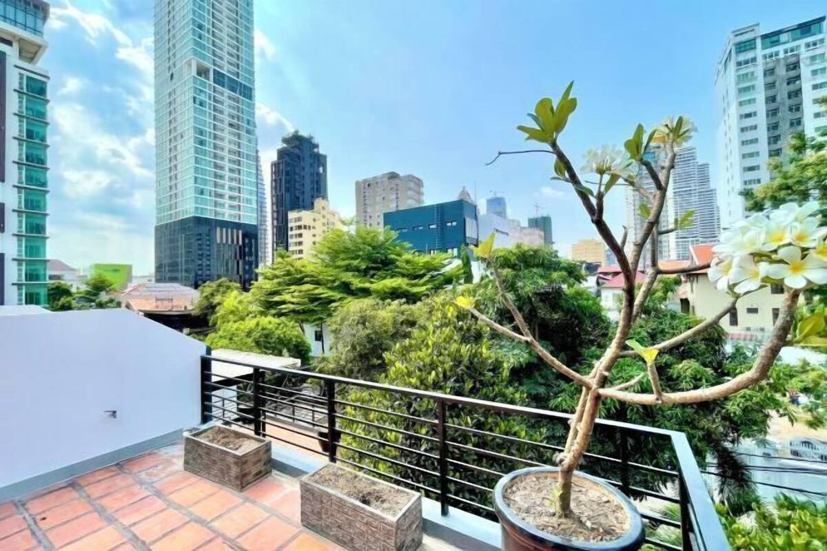 Eine Dachterrasse mit einem Topfpflanzen, einem Geländer und Blick auf umliegende Gebäude.