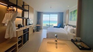 A hotel room with a large bed, a bathroom with a sink, a robe hanging on the wall, and a view of the ocean. - The Cam Ranh Oceanview (Cam Ranh)