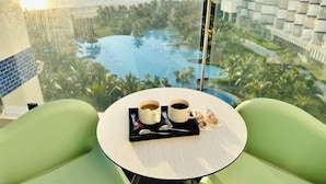A modern hotel room with a view of a resort pool and palm trees. - The Cam Ranh Oceanview (Cam Ranh)