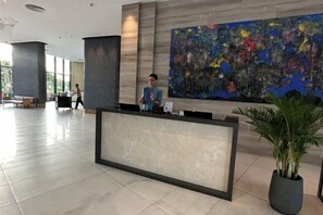 A reception area with a reception desk, a large abstract painting on the wall, and a potted plant. - The Cam Ranh Oceanview (Cam Ranh)