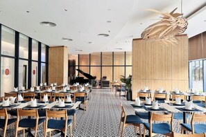 A dining area with tables and chairs, a grand piano, and a decorative ceiling feature. - The Cam Ranh Oceanview (Cam Ranh)